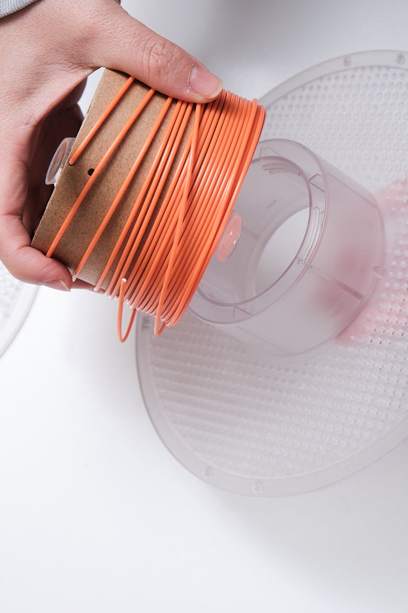Hand removing Bambu Lab Lite refill filament from reusable plastic spool system