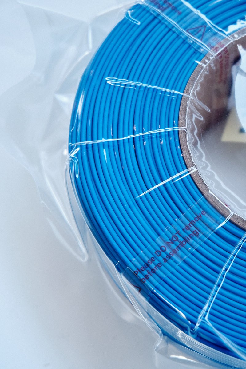 Close-up of Bambu Lab PLA Lite Blue filament showing precision neat winding in vacuum-sealed packaging.
