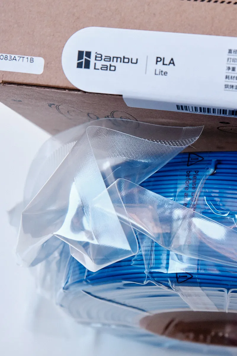Top view of vacuum-sealed Bambu Lab PLA Lite Blue filament refill with a visible RFID tag for AMS automatic recognition.