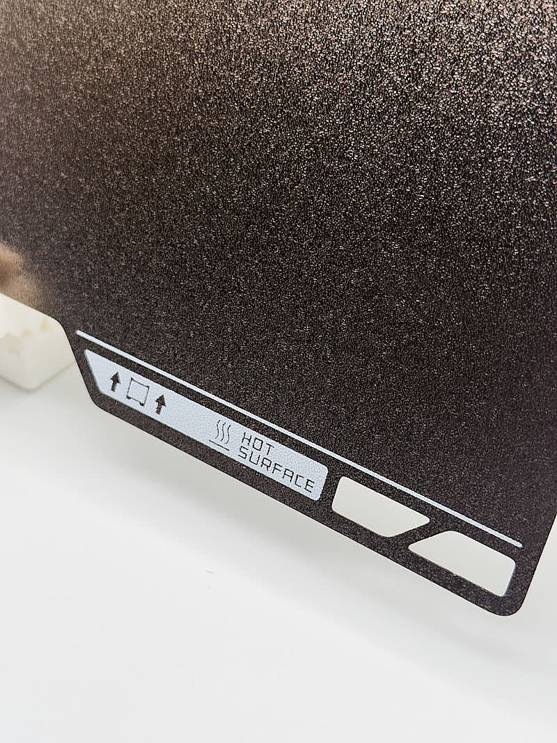 Close-up of Hot Surface warning on Bambu Textured PEI flexible build plate for H2S and H2D, indicating heat conduction from the heated bed