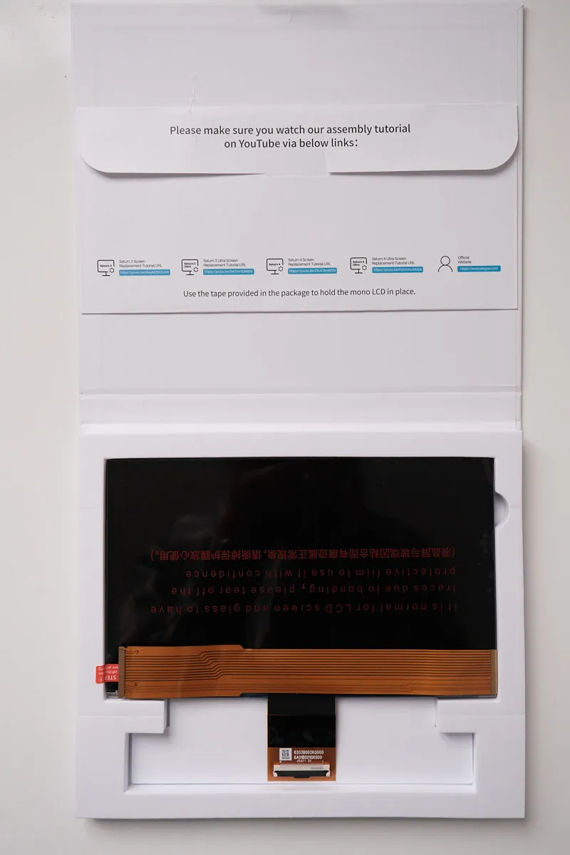 Top-down view of the Elegoo Monochrome 12K LCD screen for Saturn 3 / 3 Ultra, showing printed user instructions on the box and the LCD screen with attached ribbon cable after removing protective cardboard