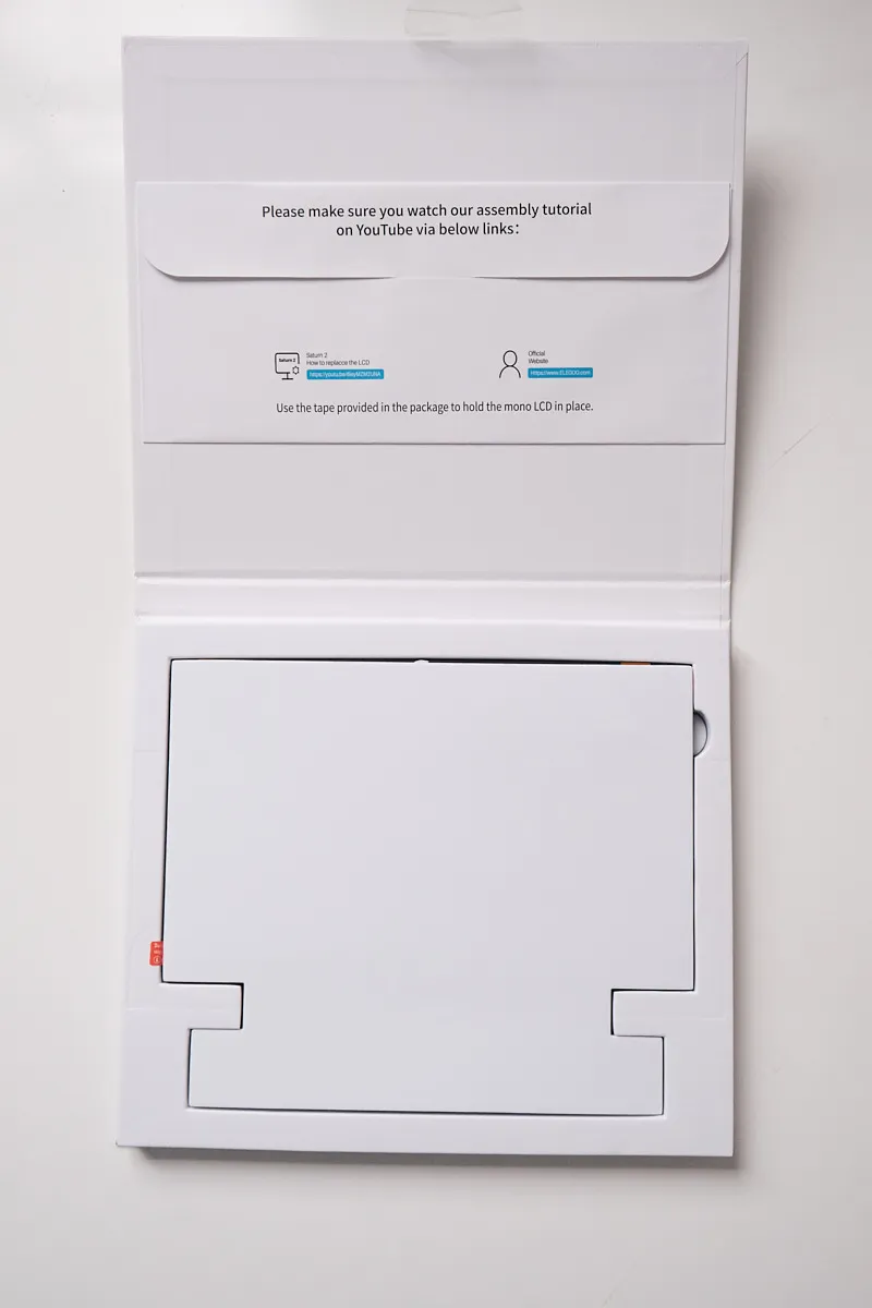 Top-down view of the Elegoo Monochrome 8K LCD screen for Saturn 2 / 8K after opening the box, showing the screen covered by external protective cardboard