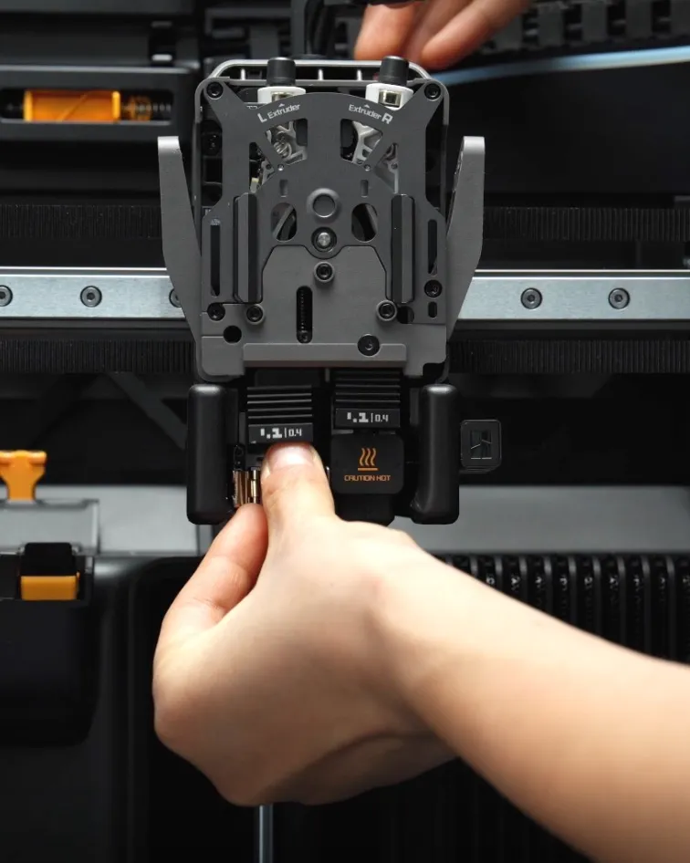Hand releasing the quick swap nozzle mechanism on a Bambu Lab hotend during nozzle removal