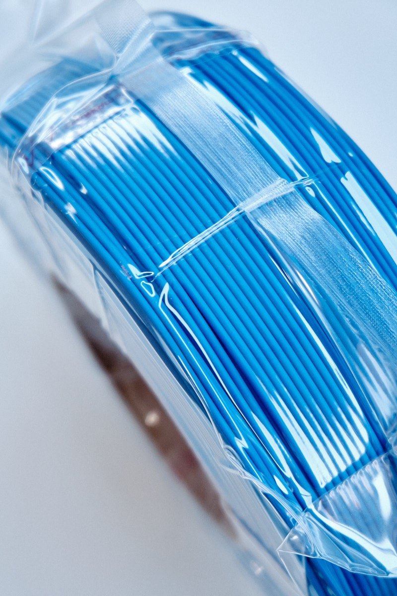Side perspective of vacuum-sealed Bambu Lab PLA Lite Blue filament showing uniform and neat winding.