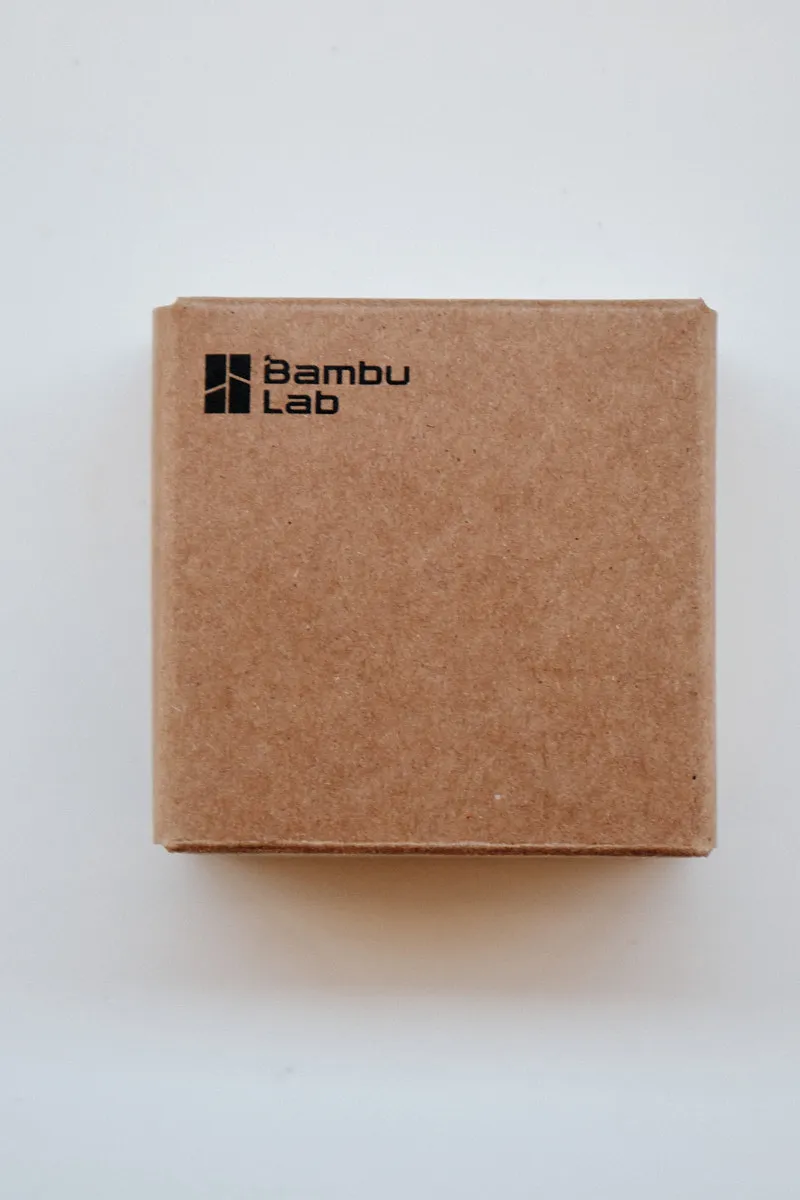 Official brown cardboard packaging for Bambu Lab 3D printer parts featuring the black logo, containing a 0.6mm High Flow hotend with a hardened steel nozzle.