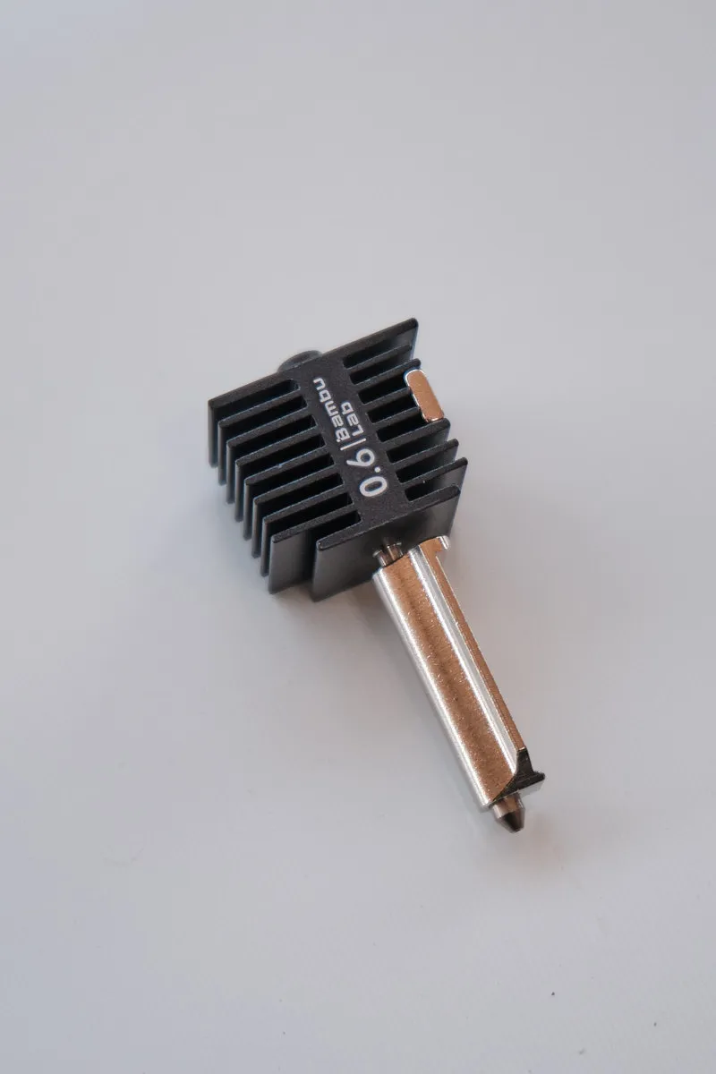 A 45-degree isometric view of the Bambu Lab A1 hotend with a 0.6mm hardened steel nozzle, featuring a black heatsink and silver-toned metal assembly on a transparent background.
