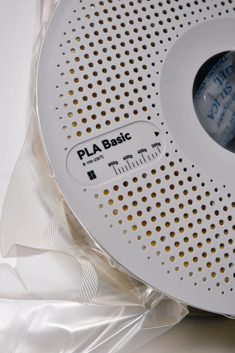 Close-up of Bambu Lab PLA Basic Yellow filament spool label showing 190-230°C printing temperature and weight indicators in vacuum packaging.