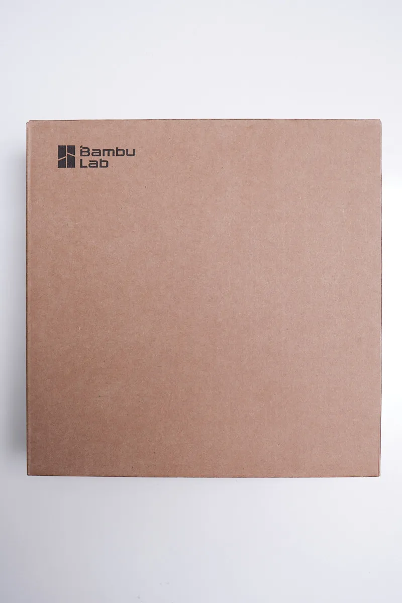 Front view of a square brown cardboard retail box for Bambu Lab 3D printing filament featuring the black Bambu Lab logo in the top left corner.