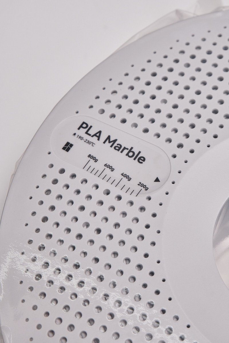 A close-up view of the label on a white Bambu Lab PLA Marble spool, showing the 190-230&deg;C printing temperature and a weight gauge for tracking remaining filament.