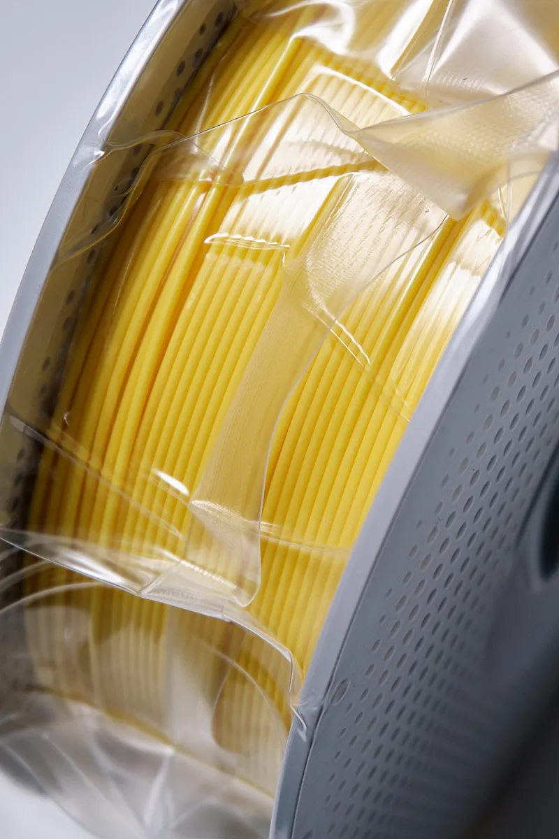 Side view of Bambu Lab PLA Basic Yellow 1.75mm filament showing neat winding and vacuum-sealed plastic packaging.