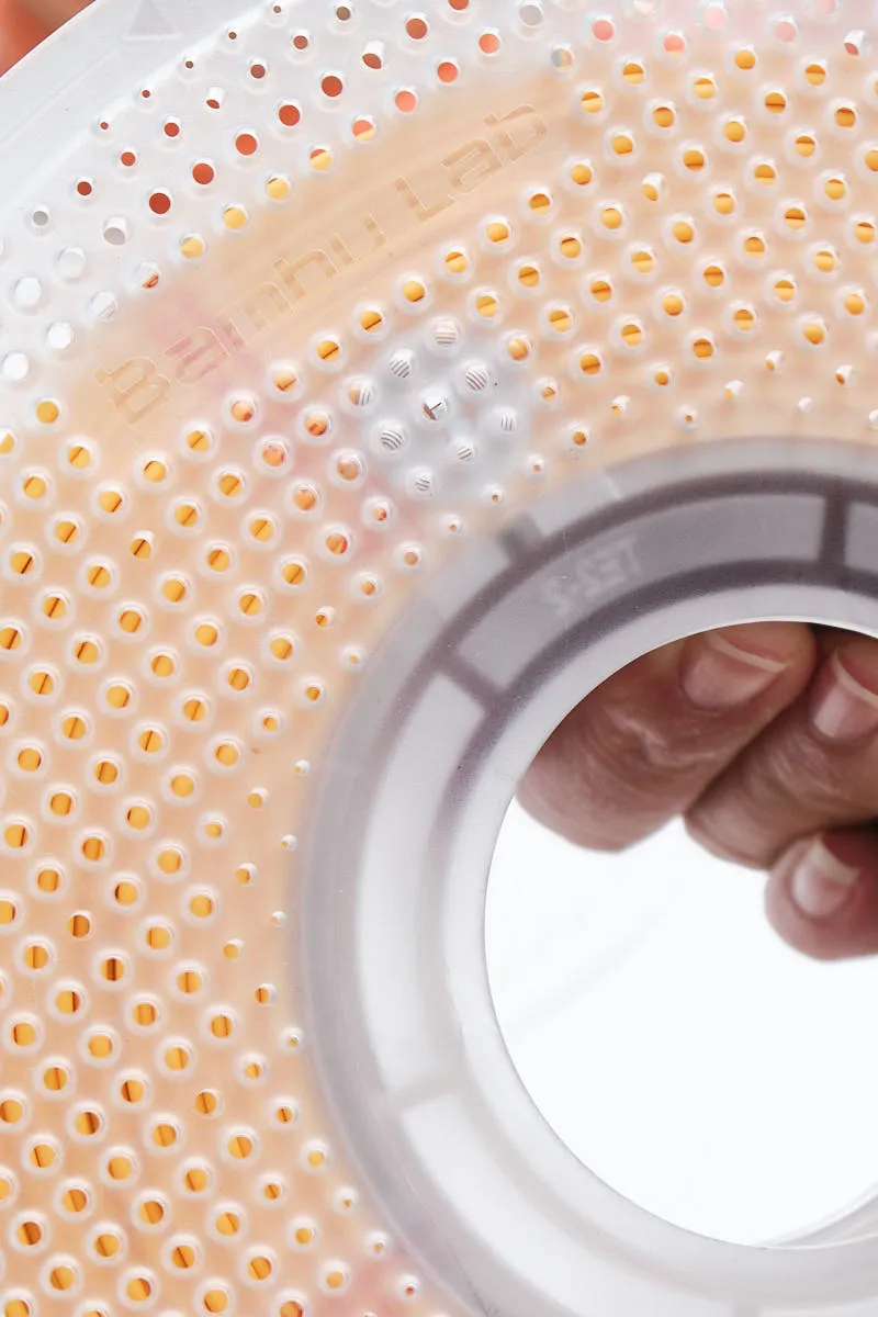 lose-up of a locked Bambu Lab reusable spool with Sunflower Yellow PLA filament inside, showing the "Bambu Lab" logo and the secured interlocking mechanism of the clear plastic sides.