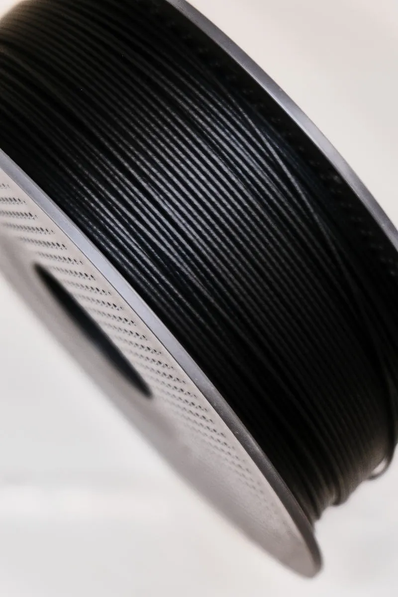 Close-up of Bambu Lab PA6-CF black 72100 filament showing carbon fiber reinforced matte texture