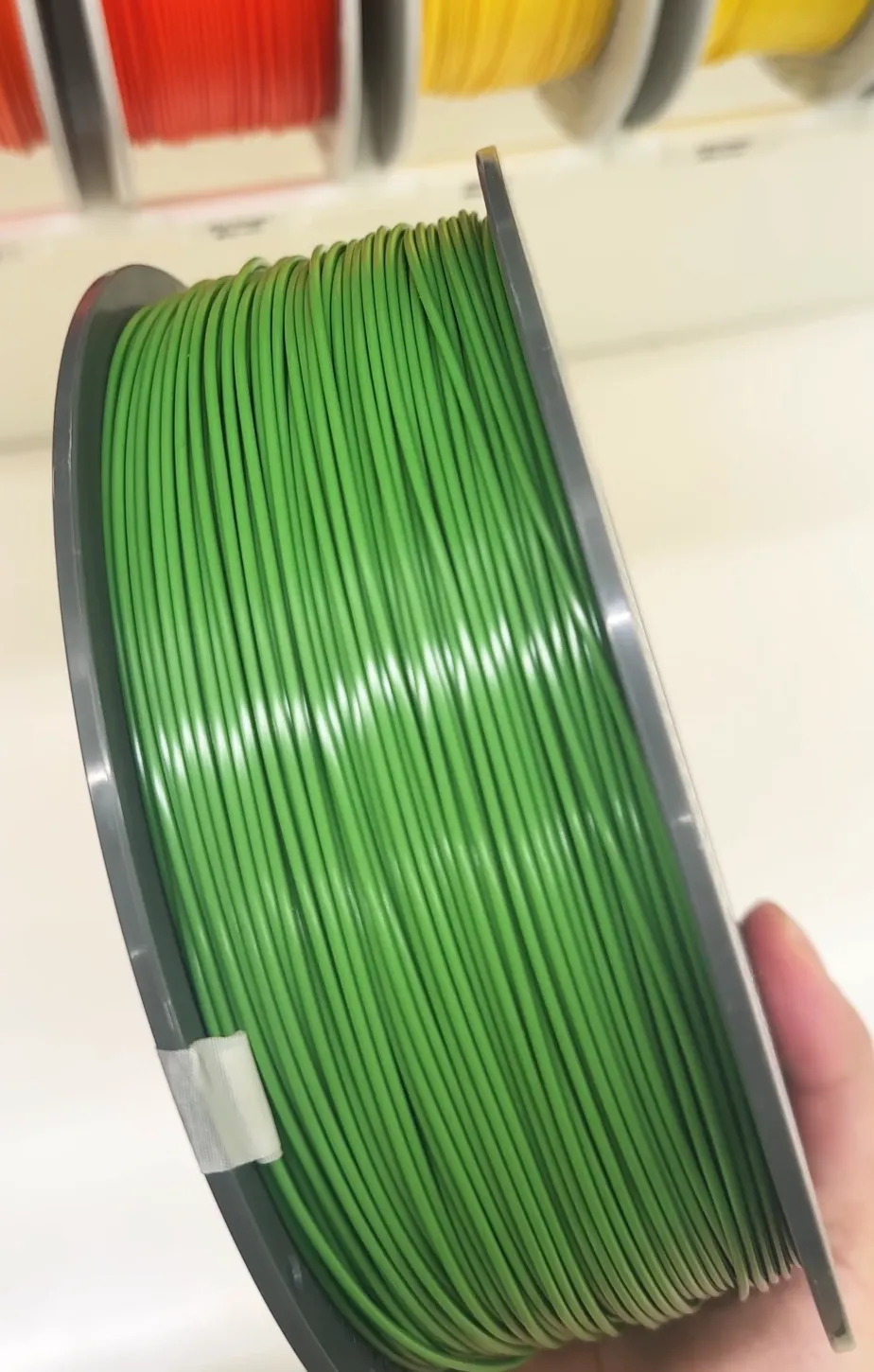 Close-up of Bambu Lab ABS Oliver Green filament 40502 on spool, showing smooth winding, consistent diameter, and solid color finish