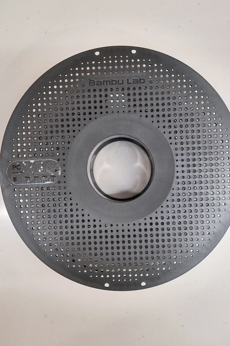Front view of Bambu Lab PC transparent filament spool with perforated design