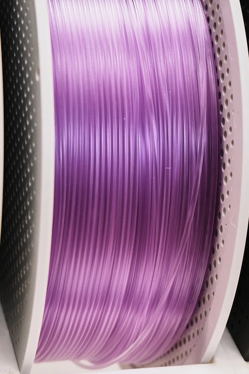 Close-up of Bambu Lab PETG Translucent Purple filament showing high transparency and smooth extrusion, color code 32700
