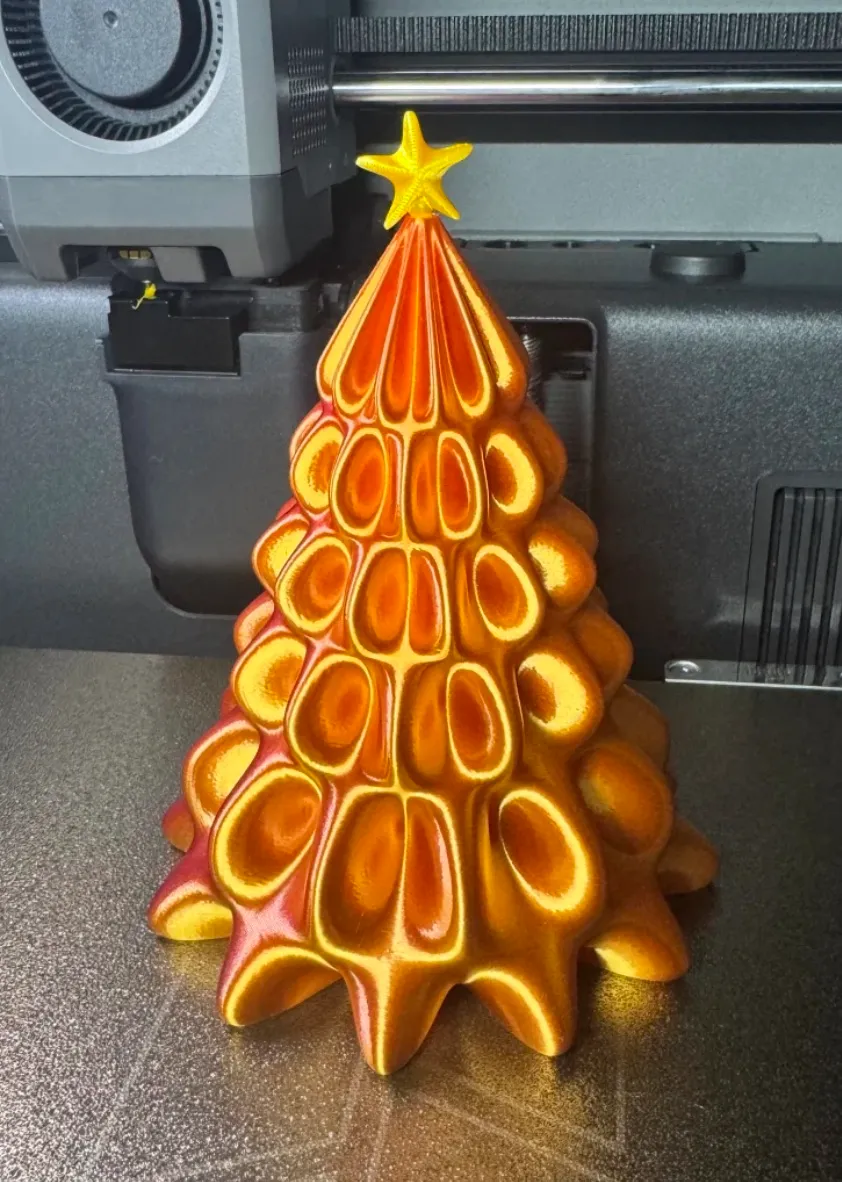 Christmas tree model 3D printed with Bambu Lab PLA Silk+ Gold filament 13405 during printing process
