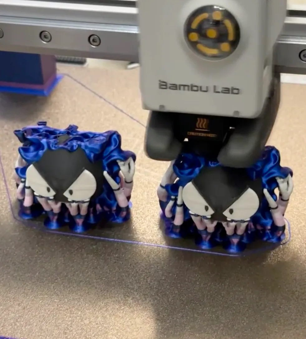 Dual figure 3D printing process using Bambu Lab PLA Silk Multi Color Neon City Filament 13903, highlighting neon color transitions during printing