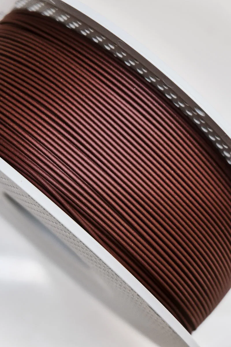 Close-up of Bambu Lab PLA Wood Rosewood Filament showing fine wood-like texture and uniform diameter, Color Code 13204