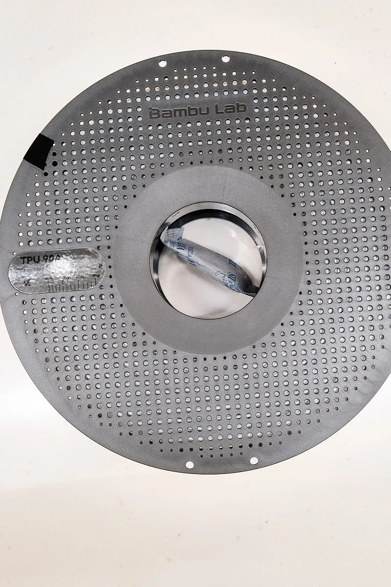 Front view of Bambu Lab TPU 90A white filament spool with perforated design