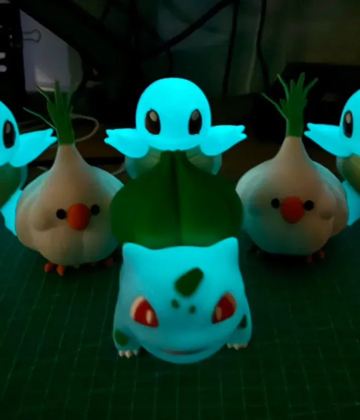 Glow-in-the-dark character figures 3D printed with Bambu PLA Glow Blue filament 15600, emitting bright blue glow in low-light conditions