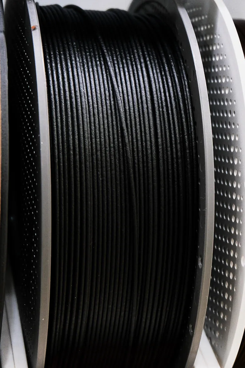 Side view of PAHT-CF black filament wound on spool with carbon fiber texture