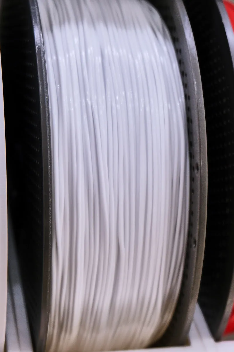 Close-up of white TPU 90A filament layers on spool under dark background, Bambu Lab Color Code 51105