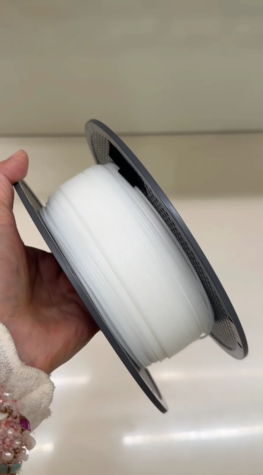 Handheld spool of Bambu Lab ABS support filament in white (color code 66100), showing filament winding and spool design