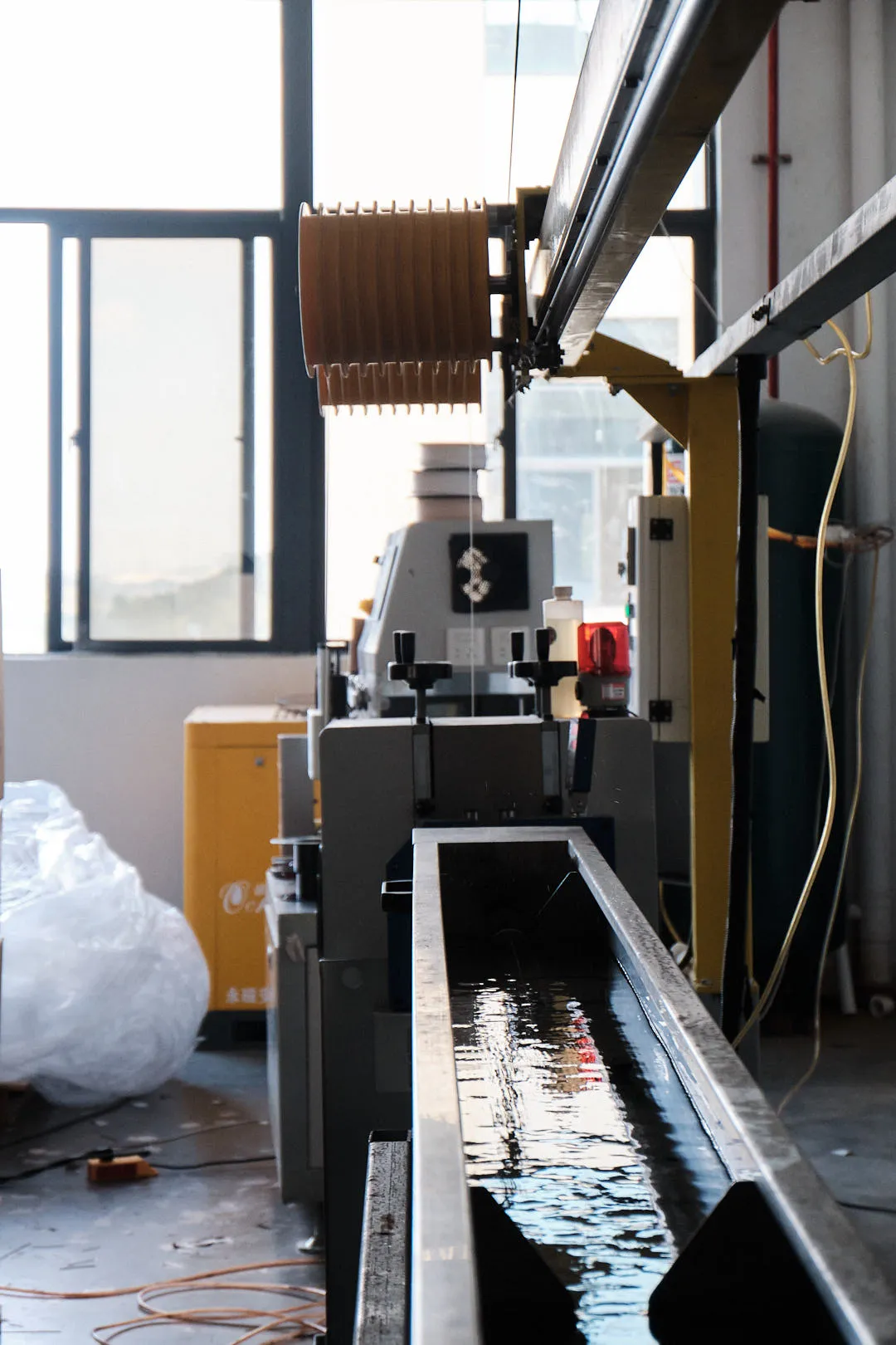 Extruded 3D printing filament passing through a water cooling trough for temperature control and shape stabilization