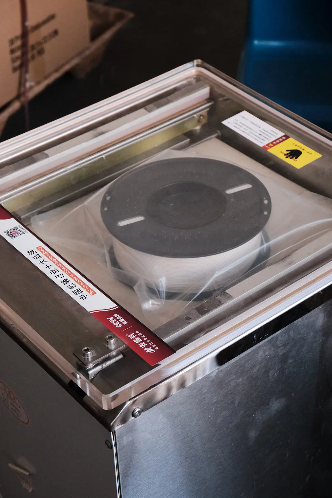 3D printing filament spool placed inside a vacuum sealing machine before packaging