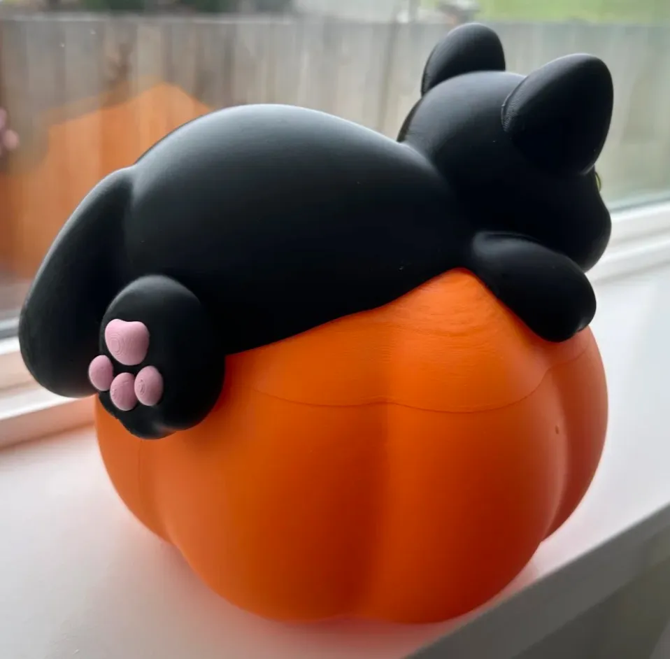 3D printed black cat resting on pumpkin-shaped container made with Bambu Lab PLA Basic Pumpkin Orange filament 10301