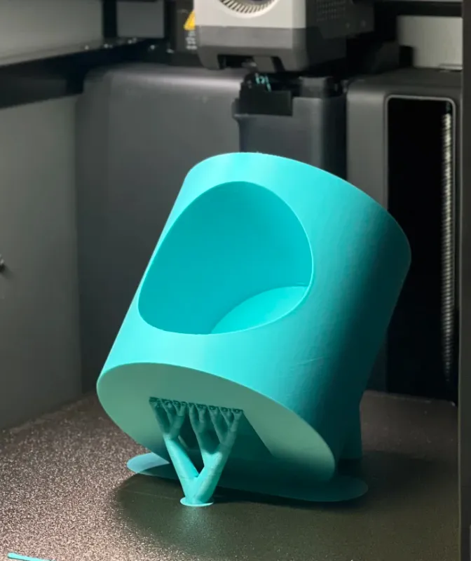 Tilted cylindrical container printed on a Bambu Lab printer using Bambu Lab PLA Basic Turquoise filament 1kg (Color Code:10605) with visible support structure underneath