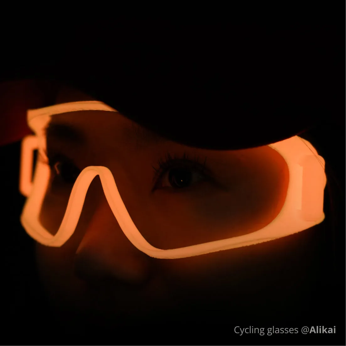 Glow-in-the-dark cycling glasses frame 3D printed with Bambu PLA Glow filament, glowing orange under low-light conditions