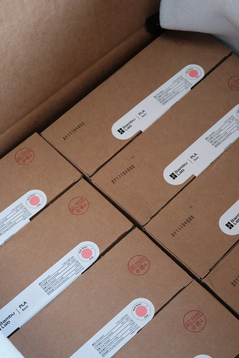 Cardboard boxes containing labeled 3D printing filament products stacked together for wholesale shipment