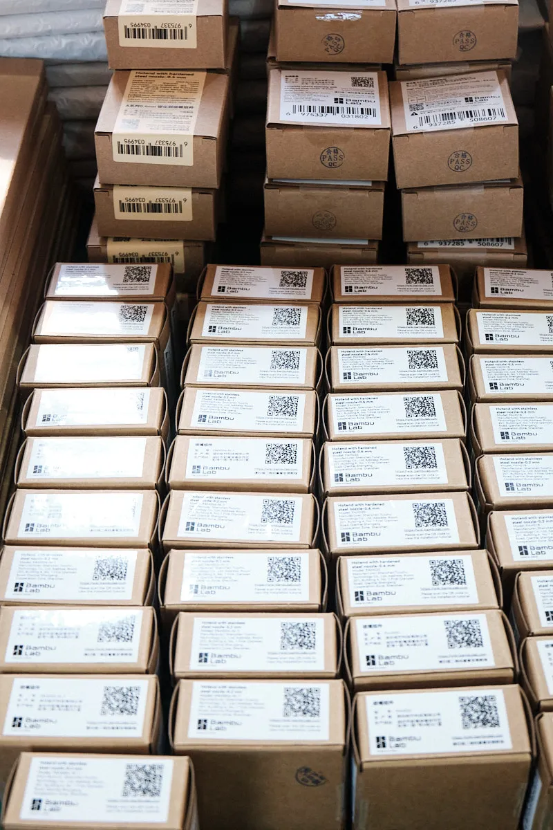 Stacks of labeled 3D printing filament boxes with barcodes and QC stamps prepared for wholesale shipment