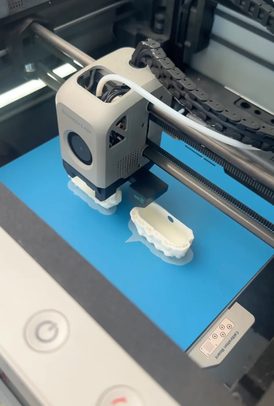 Close-up of FDM 3D printer extruder printing plastic filament on heated build plate