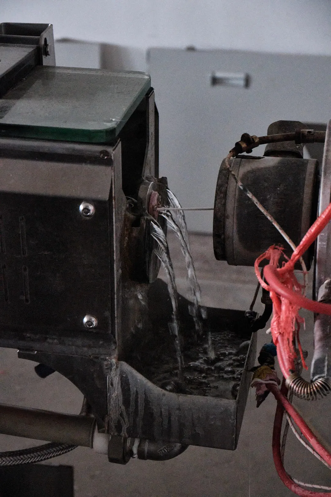 Molten plastic filament exiting the extrusion die and entering a water cooling bath during 3D printing filament production