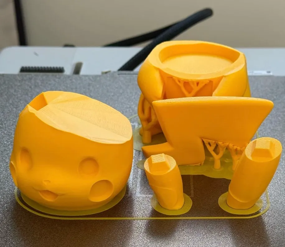 Yellow 3D printed parts with supports on build plate using PLA Basic Sunflower Yellow filament 10402