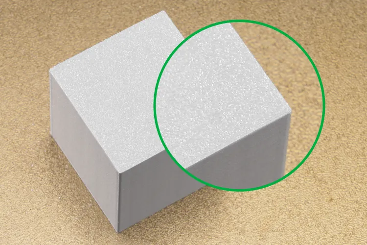 Close-up of textured bottom surface on 3D printed cube using textured PEI build plate, showing fine matte texture