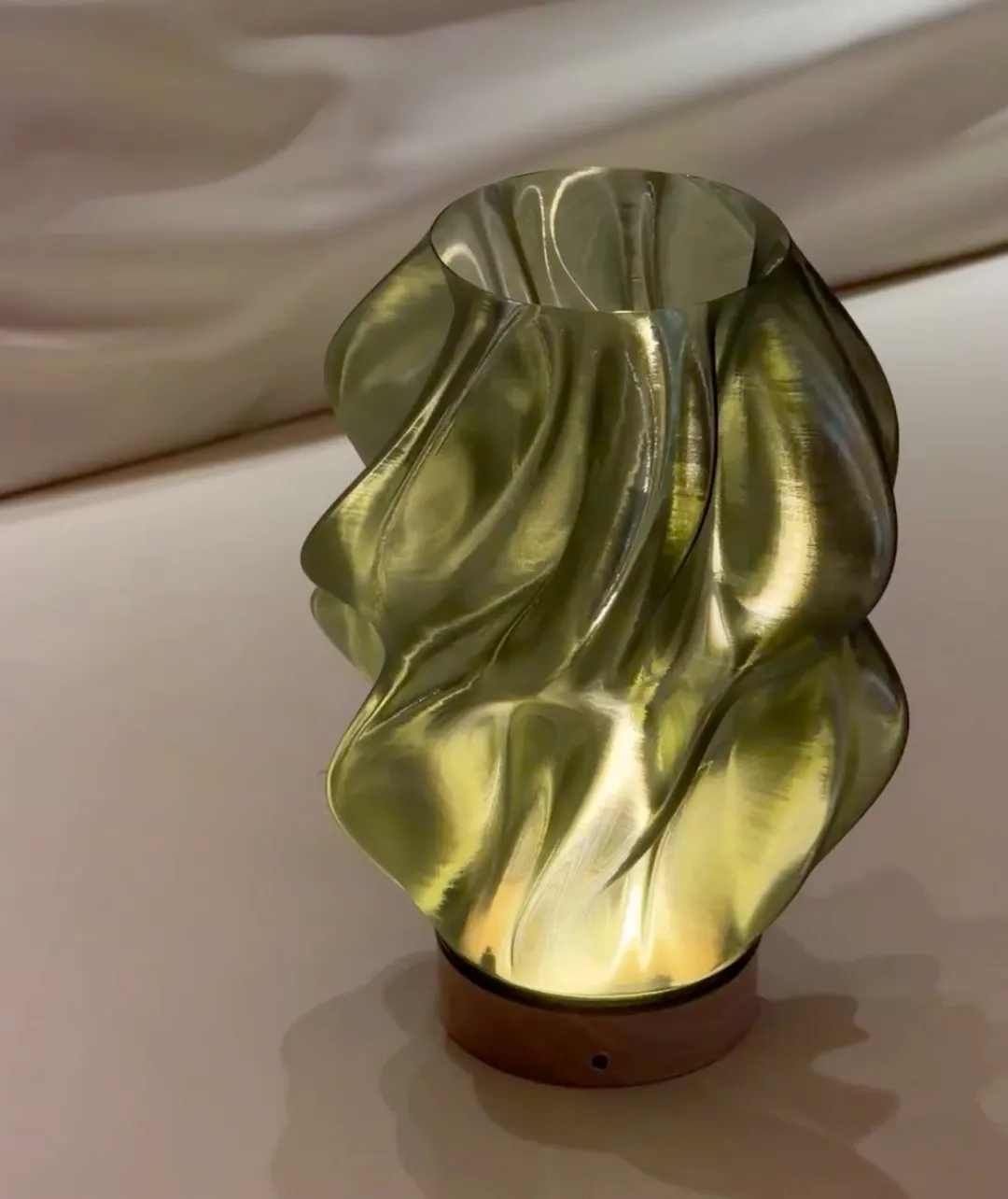 Twisted lamp shade printed with Bambu Lab PETG Translucent Olive Green Filament Color Code 32500 glowing under internal light.