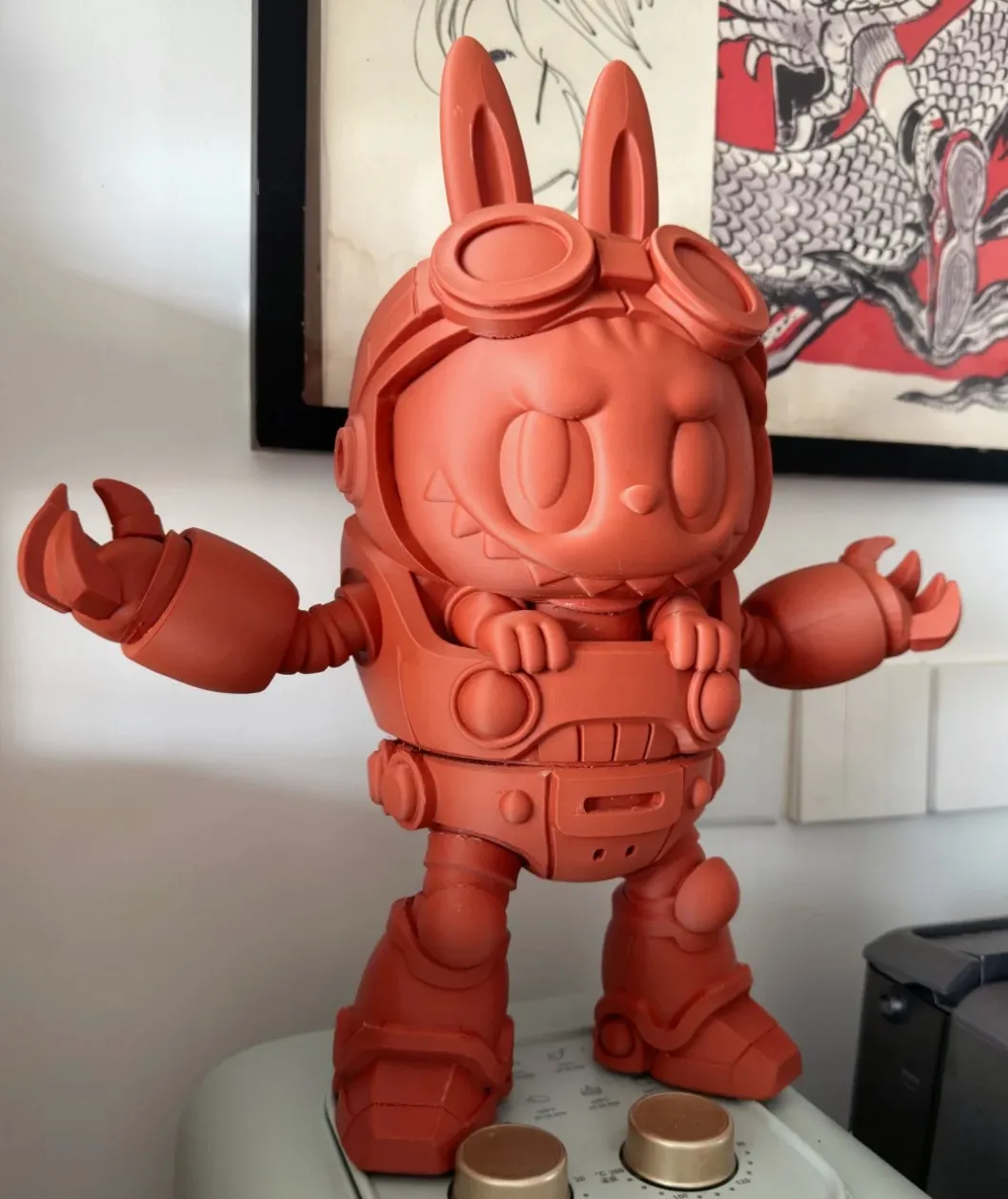 Large 3D printed character figurine in matte terracotta red with detailed mechanical suit and smooth surface finish