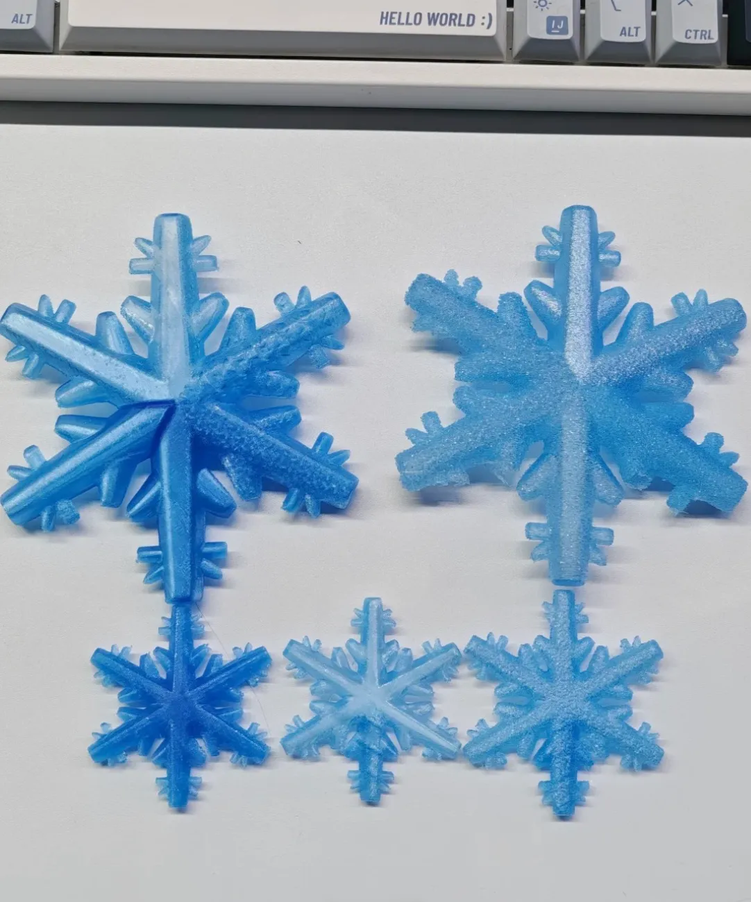 Multiple snowflake models printed in Bambu Lab PETG Translucent Light Blue Filament Color Code 32600 showing variation in translucency and surface texture.