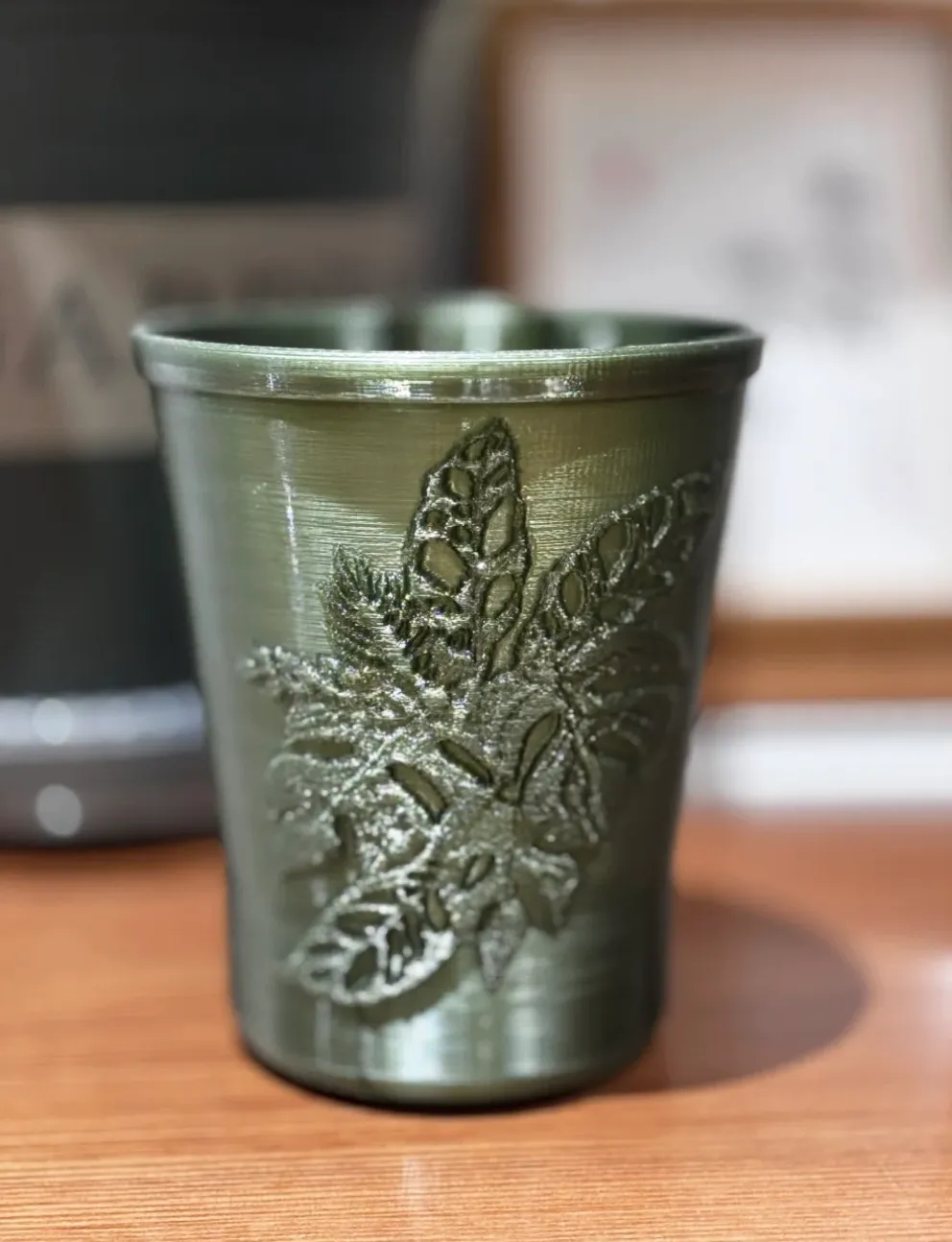 Embossed leaf-pattern cup printed with Bambu Lab PETG Translucent Olive Green Filament Color Code 32500 showing layered surface texture.