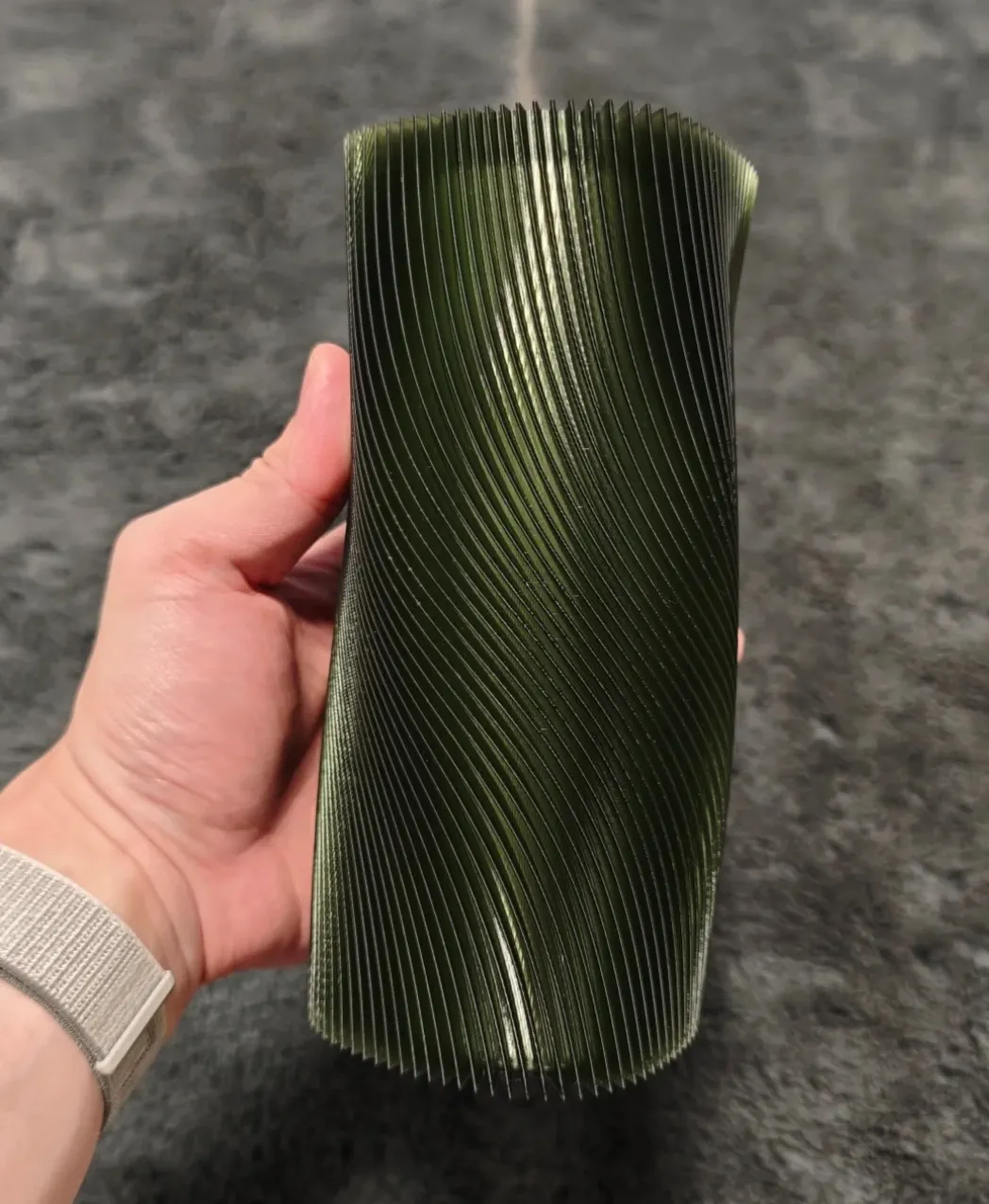 Hand holding cylindrical twisted lamp body printed with Bambu Lab PETG Translucent Olive Green Filament Color Code 32500.