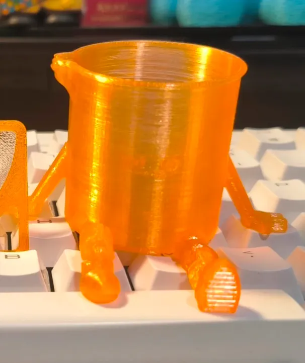 Small character-style cup printed with Bambu Lab PETG Translucent Orange Filament Color Code 32300 placed on keyboard.