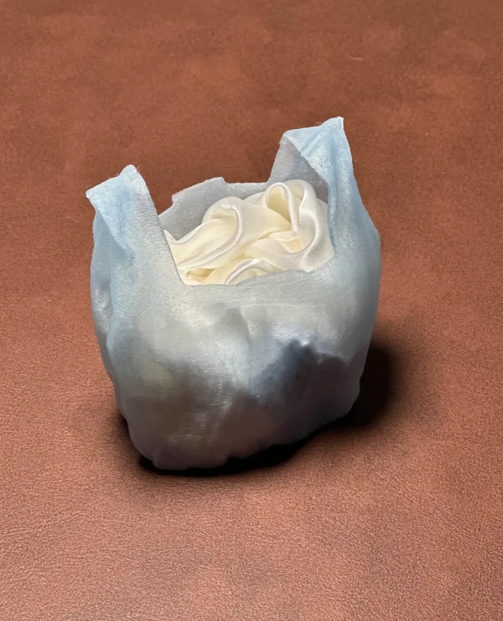 Storage container printed with Bambu Lab PLA Translucent Ice Blue Filament with Spool 13610 holding small items inside, showing semi-transparent frosted texture.