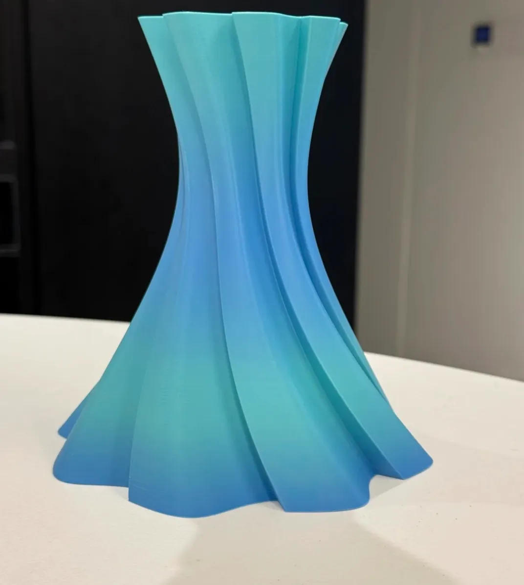 Tall twisted vase 3D print created using Bambu Lab PLA Basic Gradient Ocean to Meadow Filament with Spool with blue and green gradient effect, Color Code 10902.
