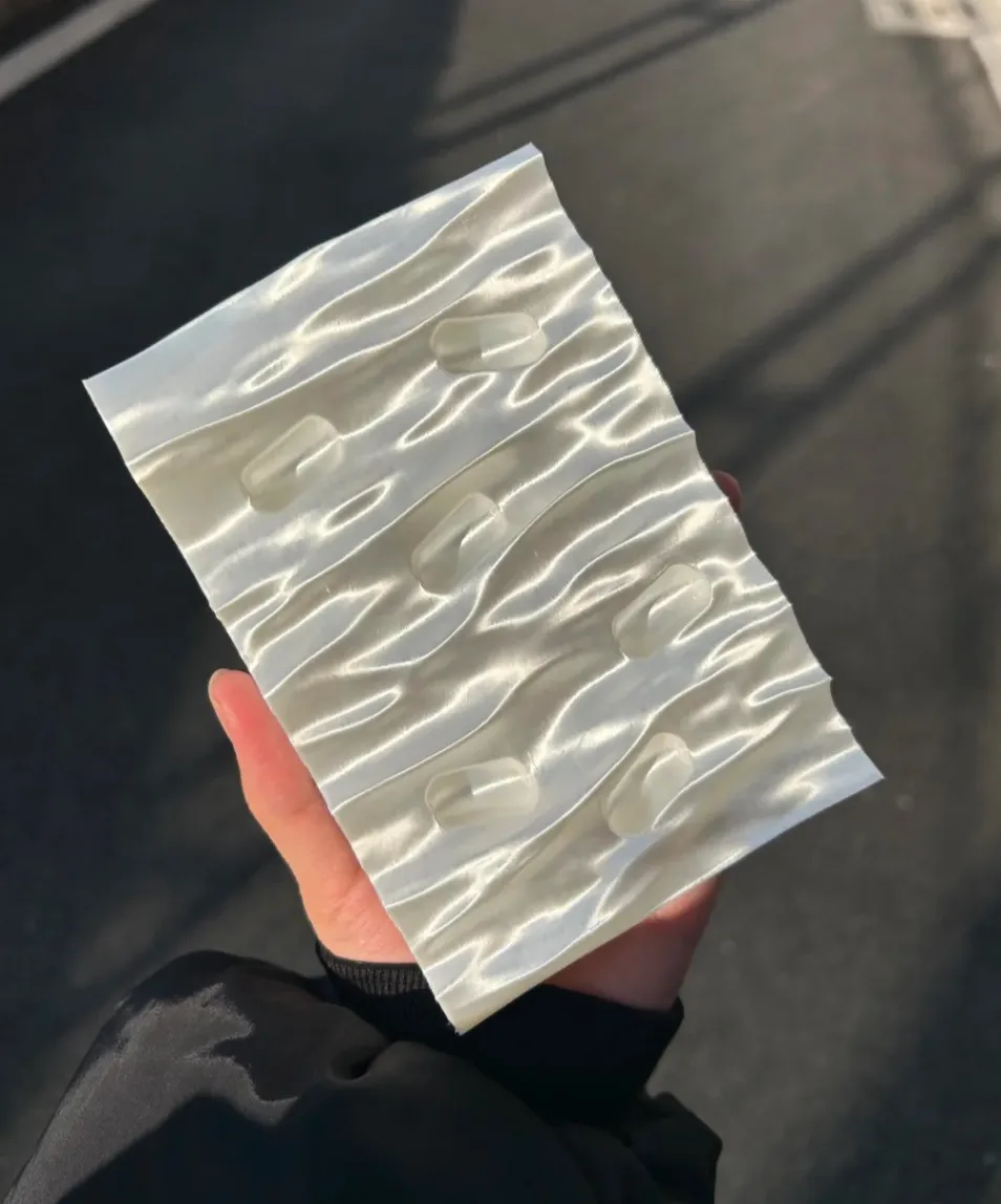 Textured 3D printed panel held in hand using Bambu Lab PLA Silk+ White Filament 1.75mm 1kg/Spool Color Code 13110 with silk surface reflection