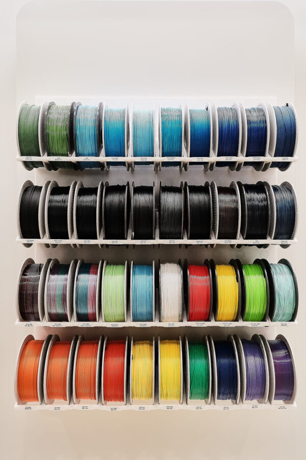 multiple 3d printer filament spools arranged on wall rack with blue black green and mixed color filaments