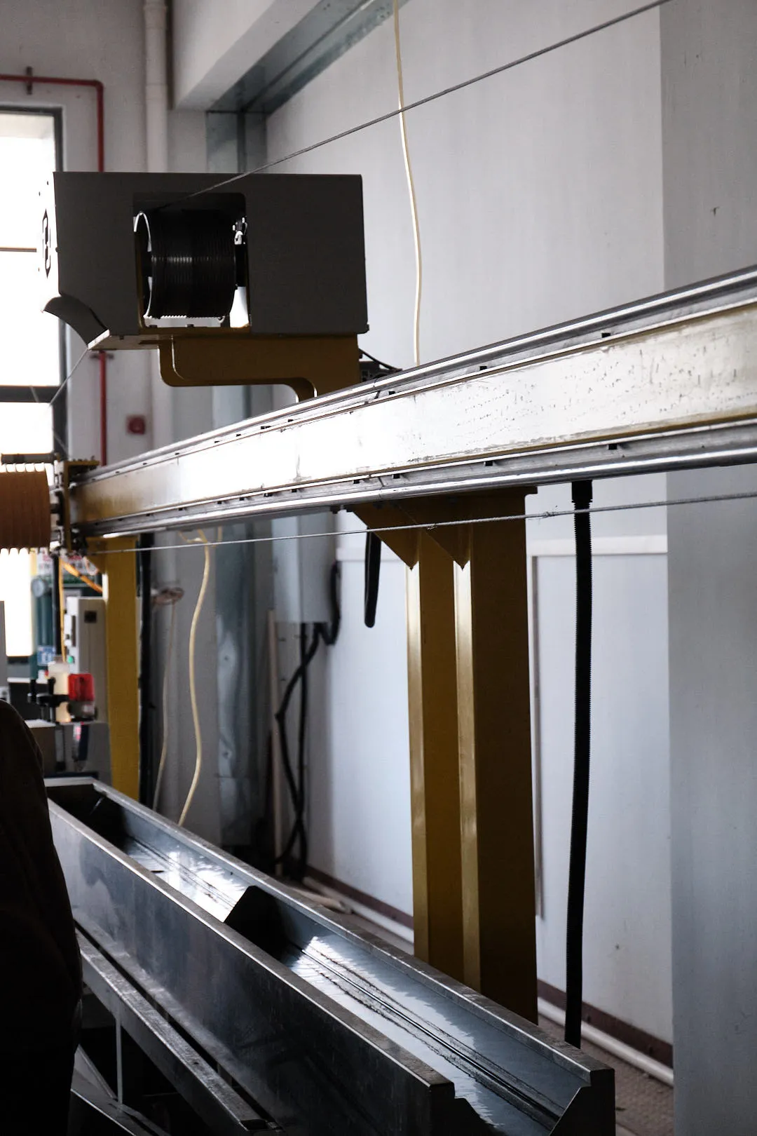 3D printing filament being guided along a long cooling line in a factory extrusion process