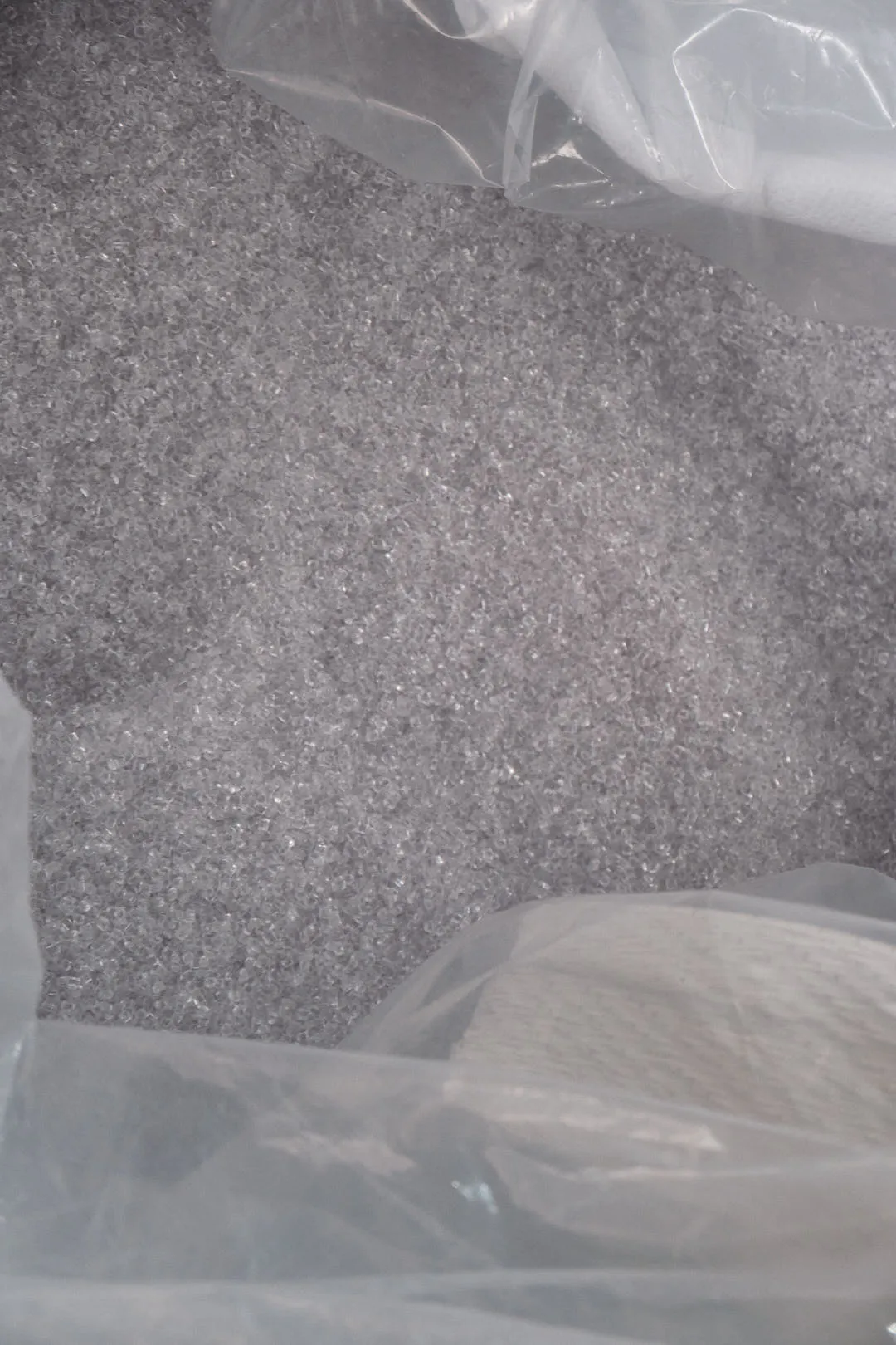 transparent plastic pellets used for 3D printing filament inside a plastic bag
